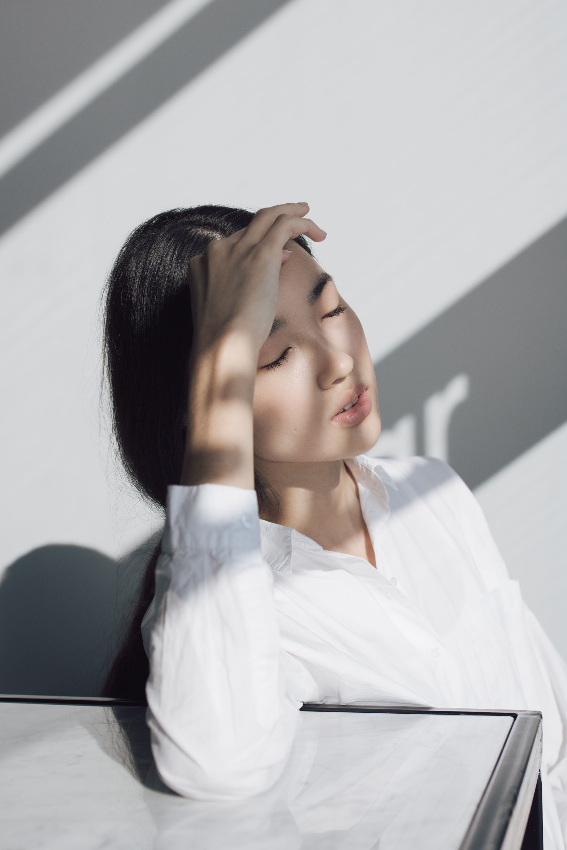 a woman with her eyes closed and hand on her forehead